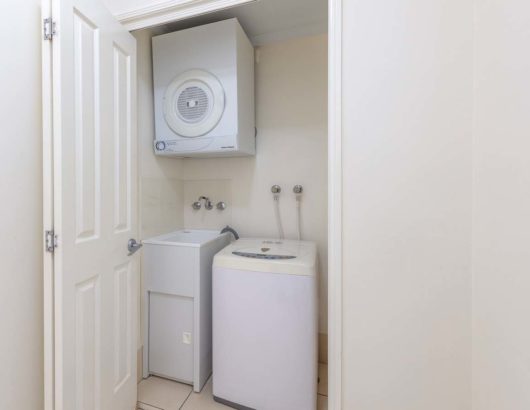 Closet in a Park Regis City Quays apartment with a top-load washer, front-load dryer, and sink