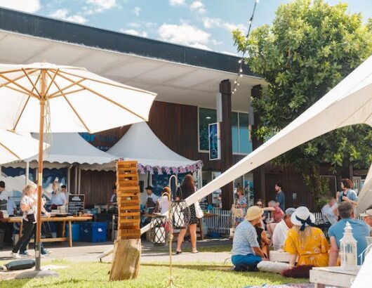 People outside at Salt House Food & Wine Festival under a large tent and umbrellas